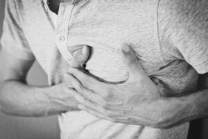 Man with lupus with hands on his chest during a heart attack