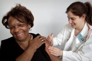 Black middle aged black doctor giving a heavy set white woman with lupus a flu shot