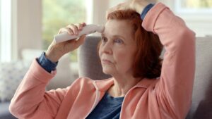 Woman holding thermometer to head during what is a lupus flare